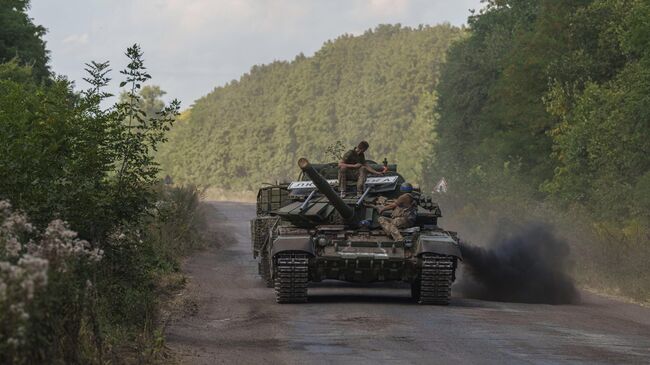 Украинские военнослужащие едут на танке с табличкой Любимовка недалеко от российско-украинской границы в Сумской области. Архивное фото