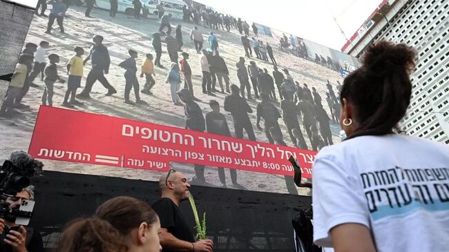 Люди смотрят прямую трансляцию освобождения заложников из сектора Газа в Тель-Авиве, Израиль. 13 октября 2025