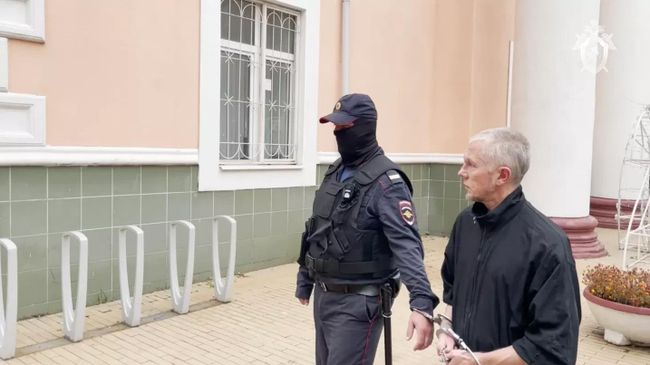 Мужчина, обвиненный в изнасилованиях и убийствах девушек 20-летней давности, в сопровождении сотрудника полиции. Архивное фото
