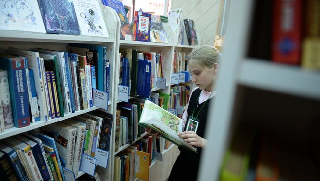 Девочка читает книгу в библиотеке