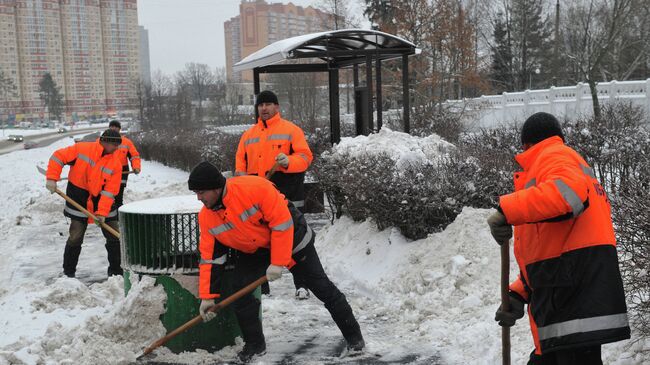 Сотрудники коммунальных служб убирают снег с территории автобусной остановки