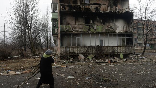 Жительница города Дебальцево несет ветви деревьев для разжигания костра, на котором жильцы пострадавших жилых домов, готовят еду