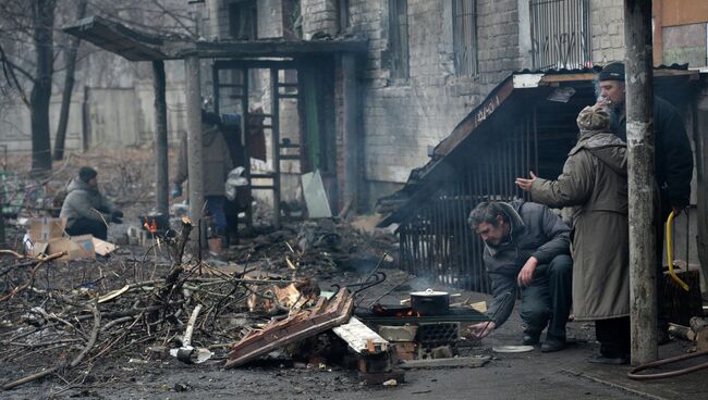 Жители города Дебальцево готовят еду на костре у подъезда жилого многоквартирного дома, пострадавшего в результате боевых действий