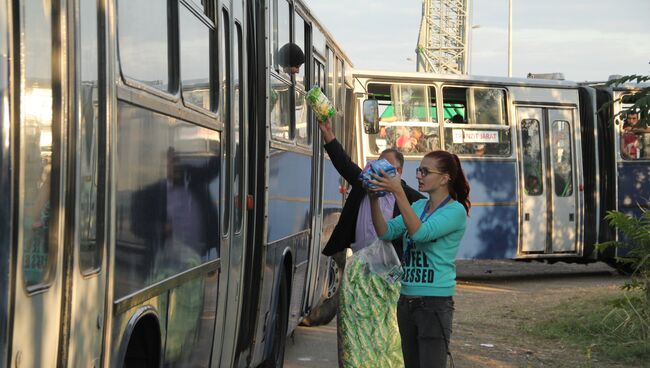 Волонтеры передают воду беженцам, ожидающим отправки в миграционный лагерь. Архивное фото