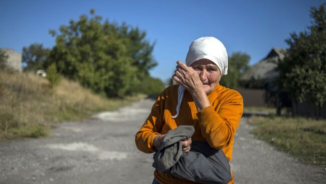 Местная жительница наблюдает за проходом колонны машин 38-го гуманитарного конвоя в Донецкой области