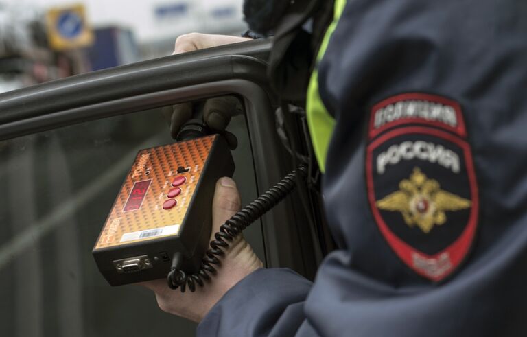 Сотрудник ГИБДД проверяет с помощью прибора тонировку стекла автомобиля в рамках рейда скрытых патрулей ДПС в Москве