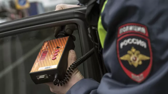 Сотрудник ГИБДД проверяет с помощью прибора тонировку стекла автомобиля в рамках рейда скрытых патрулей ДПС в Москве