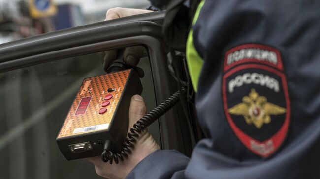 Сотрудник ГИБДД проверяет с помощью прибора тонировку стекла автомобиля в рамках рейда скрытых патрулей ДПС в Москве