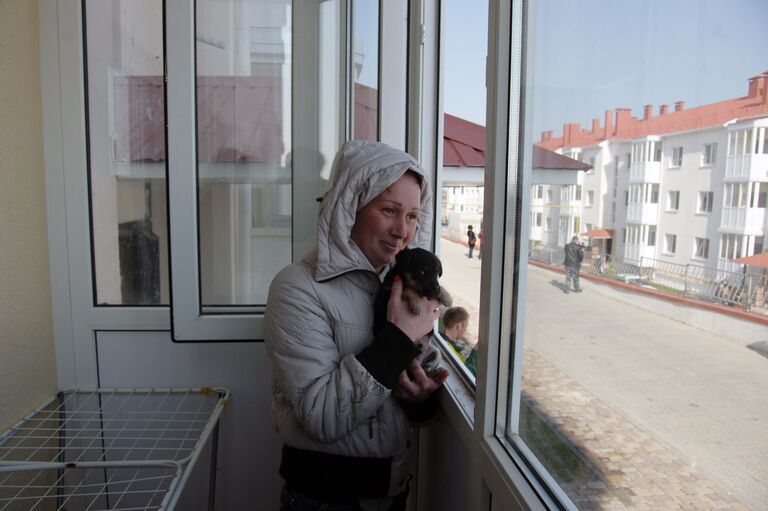 Женщина на балконе в новой квартире в Крыму, переехавшей из зоны строительства Керченского моста Женщина на балконе в новой квартире в Крыму, переехавшей из зоны строительства Керченского моста