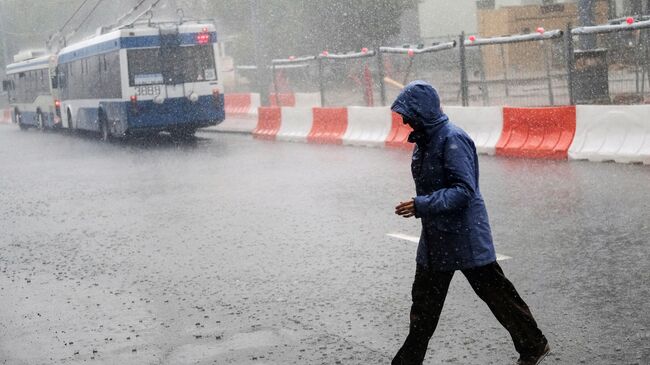 Прохожий во время ливня на одной из улиц Москвы