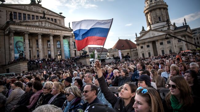 Посетители концерта Песни Победы на площади Жандарменмаркт в центре Берлина