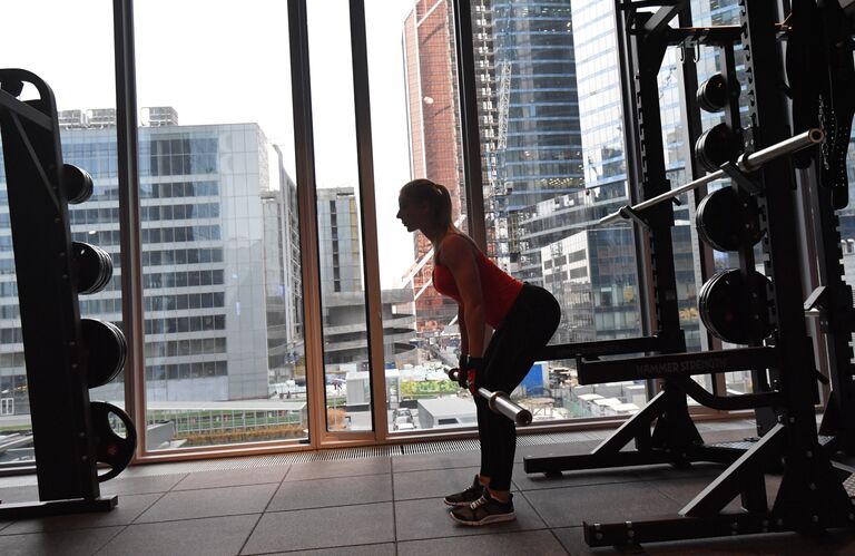 Девушка занимается со штангой в фитнес-клубе