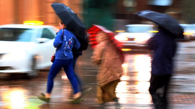 Пешеходы на улице в Москве во время сильного дождя