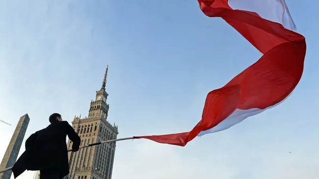 Мужчина держит польский флаг во время празднования Дня независимости в Варшаве