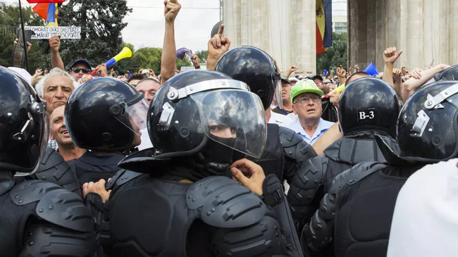 Сотрудники правоохранительных органов и участники акции протеста, требующие отставки правительства, в Кишиневе. 26 августа 2018