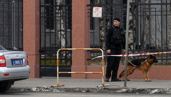 Сотрудник полиции с собакой у входа в здание управления ФСБ по Архангельской области, где произошел взрыв