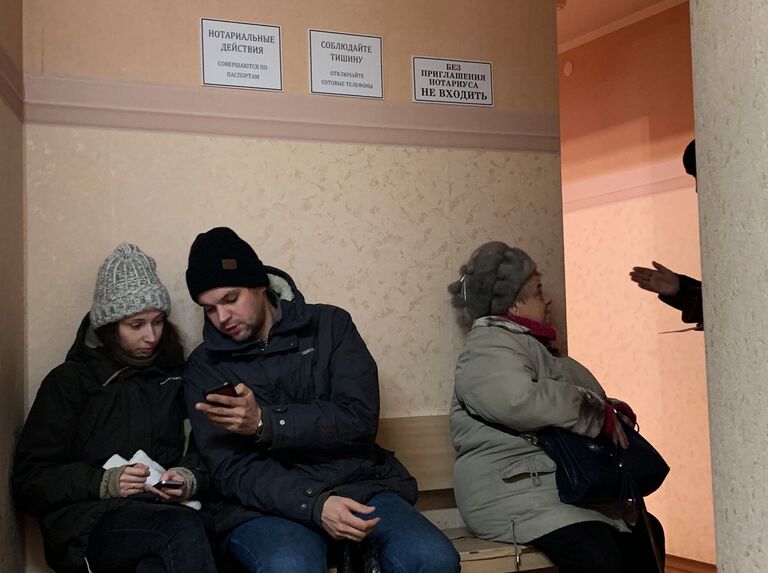 Люди сидят в очереди к нотариусу Люди сидят в очереди к нотариусу