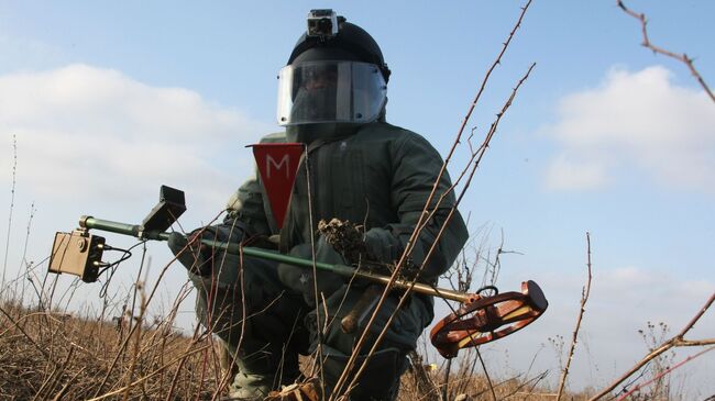 Сапер инженерных войск ЮВО в защитном костюме во время разминирования местности в в Чеченской Республике