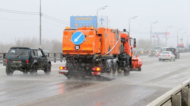 Снегоуборочная машина обрабатывает улицу противогололедным средством