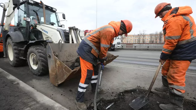 Рабочий бригады ГБУ Автомобильные дороги демонтирует старое дорожное полотно