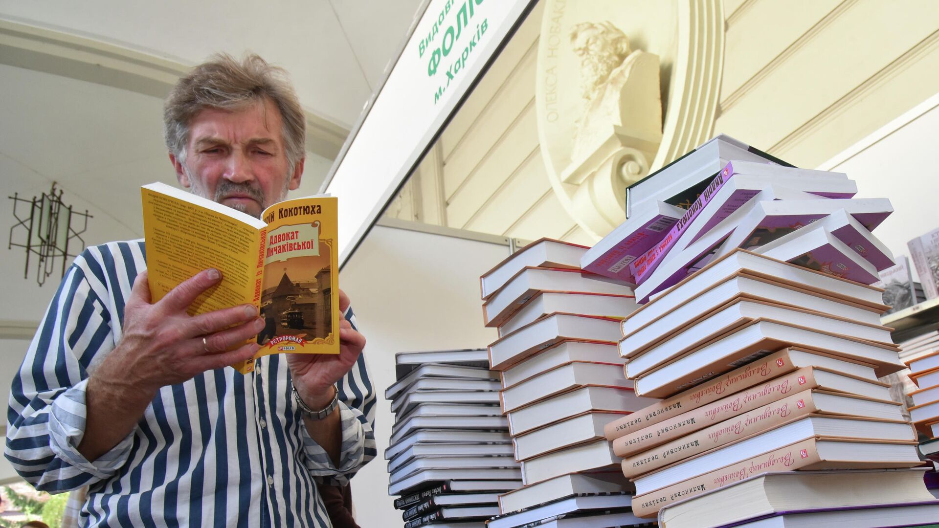 Посетитель читает книгу на книжной ярмарке во Львове - РИА Новости, 1920, 09.11.2025