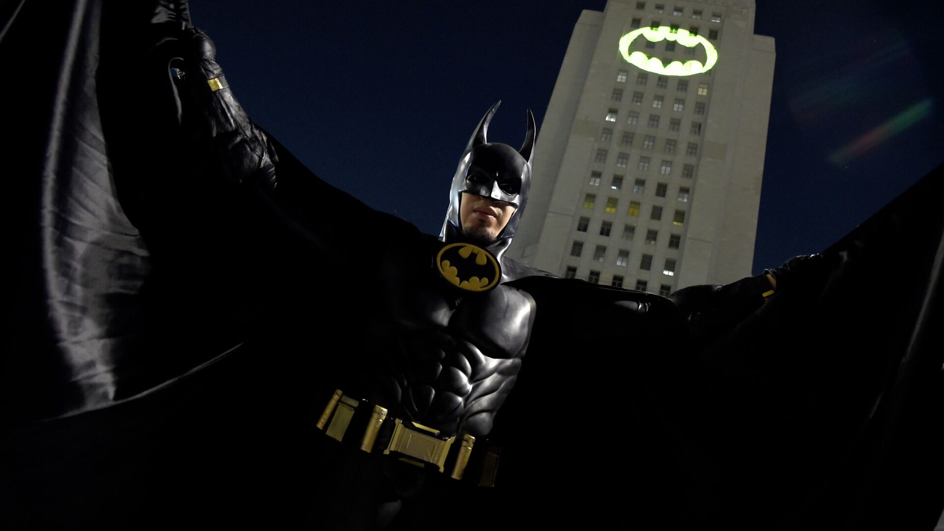 Мужчина позирует перед Bat-Signal, проецируемым на здание муниципалитета в Лос-Анджелесе - РИА Новости, 1920, 02.04.2025