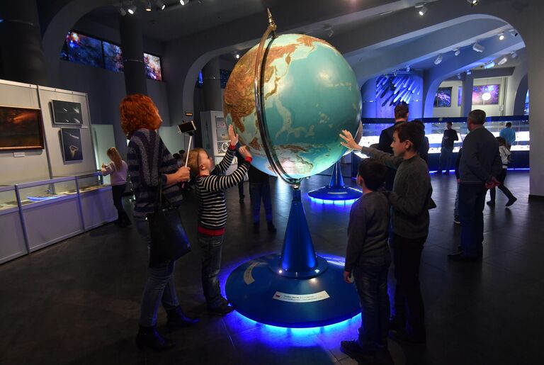 Посетители у глобуса Земли в музее Урании Московского планетария