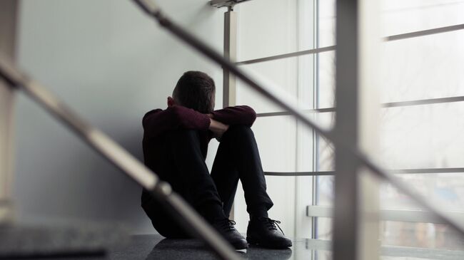 Грустный мальчик сидит на лестнице