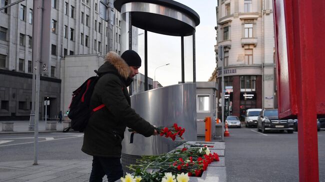 Молодой человек оставляет цветы у площади Воровского на пересечении улиц Кузнецкий мост и Большая Лубянка