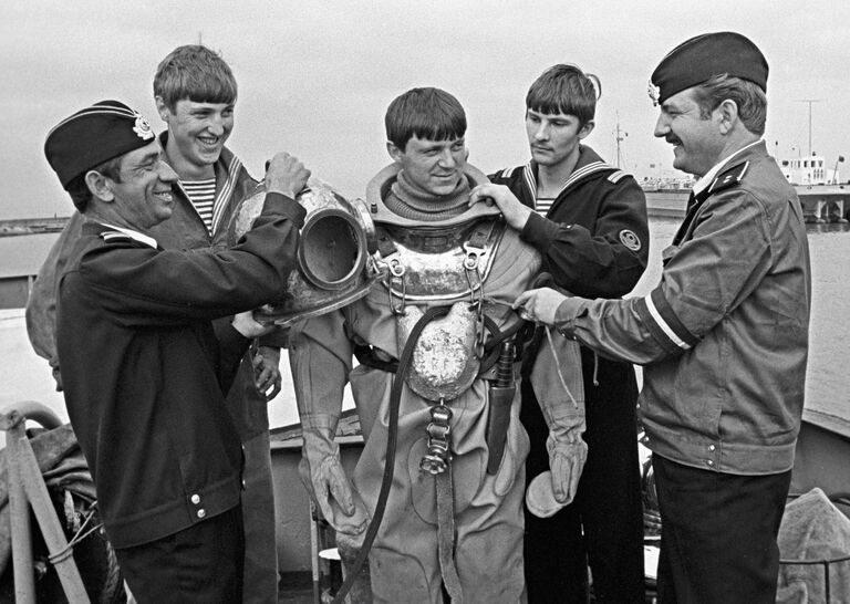 Зиганшин помогает водолазу одевать скафандр